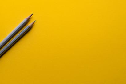 Two grey pencils on a bright yellow background