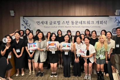A group of SAF alumni gather, proudly holding signs representing the European cities where they completed their IES internships.