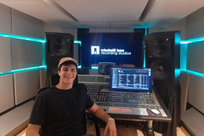 student smiling with hat on in front of audio visual equipment