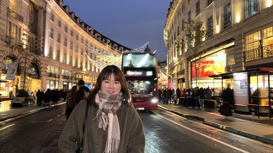 A student poses on the high street of Central London at night