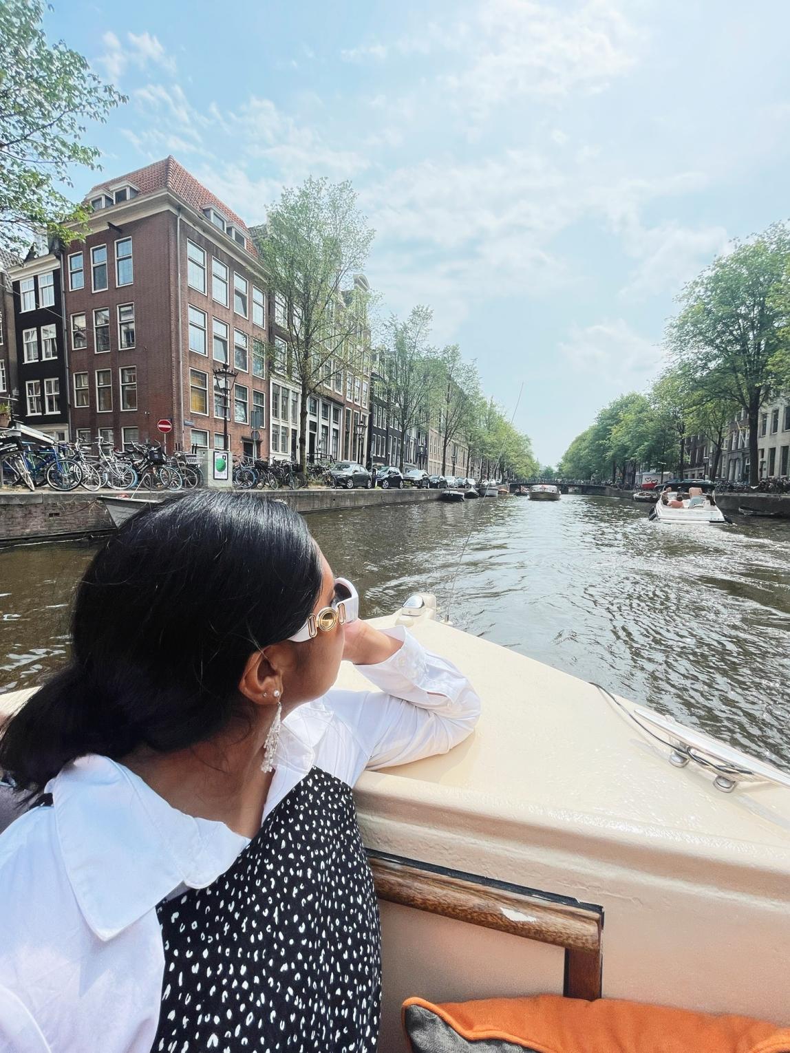 a student riding through the Amsterdam canals on a boat