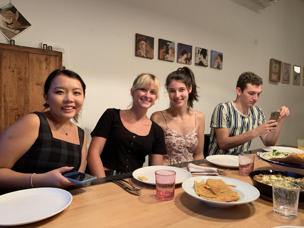 Students with their host mom seated around a dinner table at a homestay in Nice.