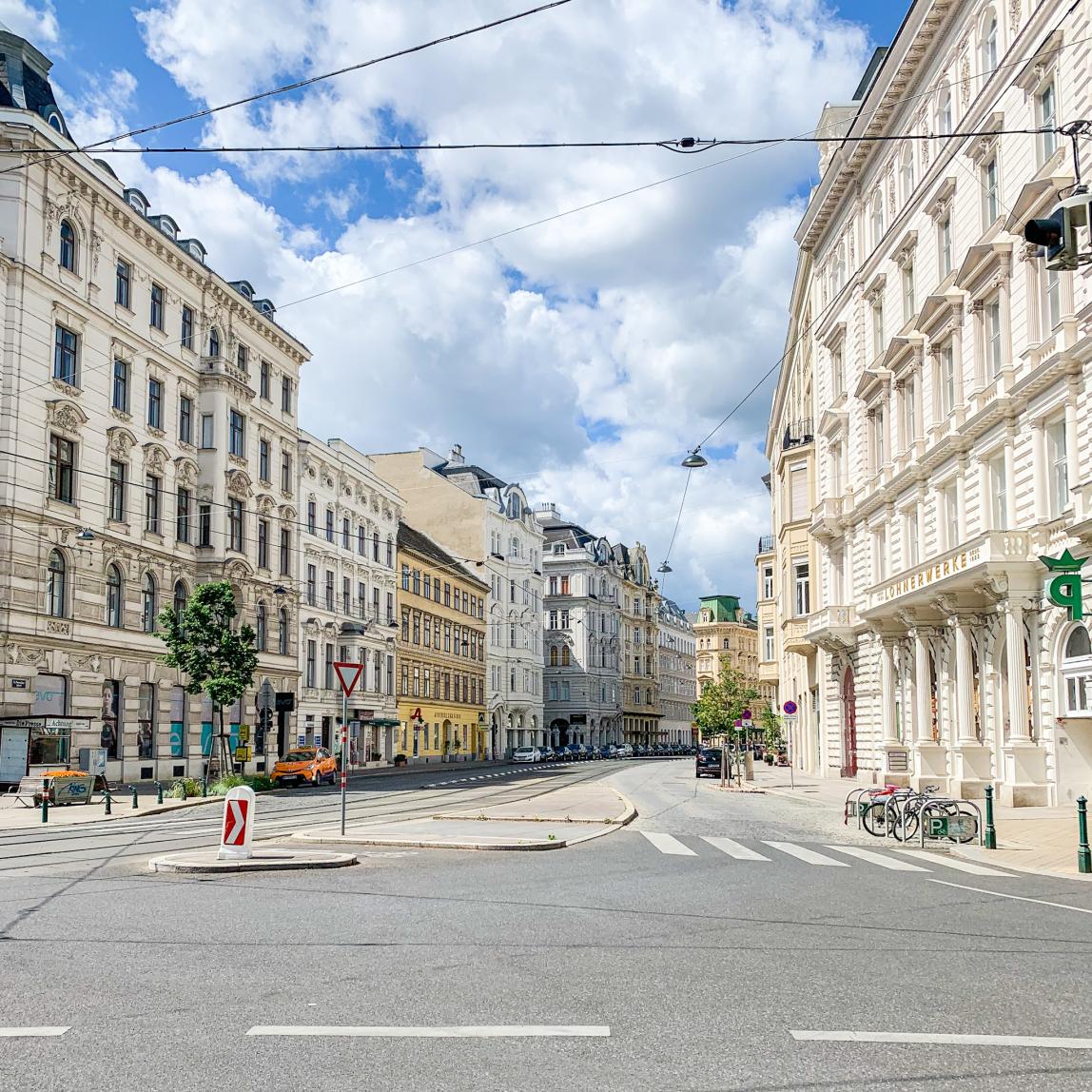 An empty street in Vienna, Austria lined with white buildings.