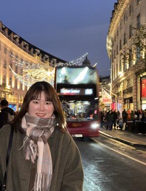 A student poses on the high street of Central London at night