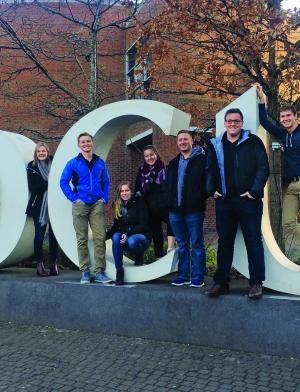 Students stand on Dublin City University's giant letter display. The letters are "DCU."