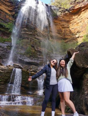 Students standing underneath a waterfall on a sunny day.