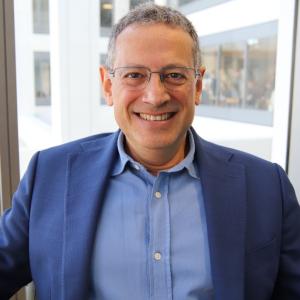 Headshot of Roberto Andreoni smiling against a window backdrop