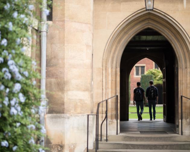 two students walking under large building with pointed arch