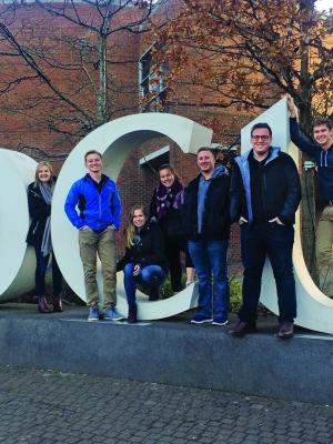 Students stand on Dublin City University's giant letter display. The letters are "DCU."