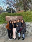 Students pose outside of Nanzan University's sign. The text reads: "Nanzan University."